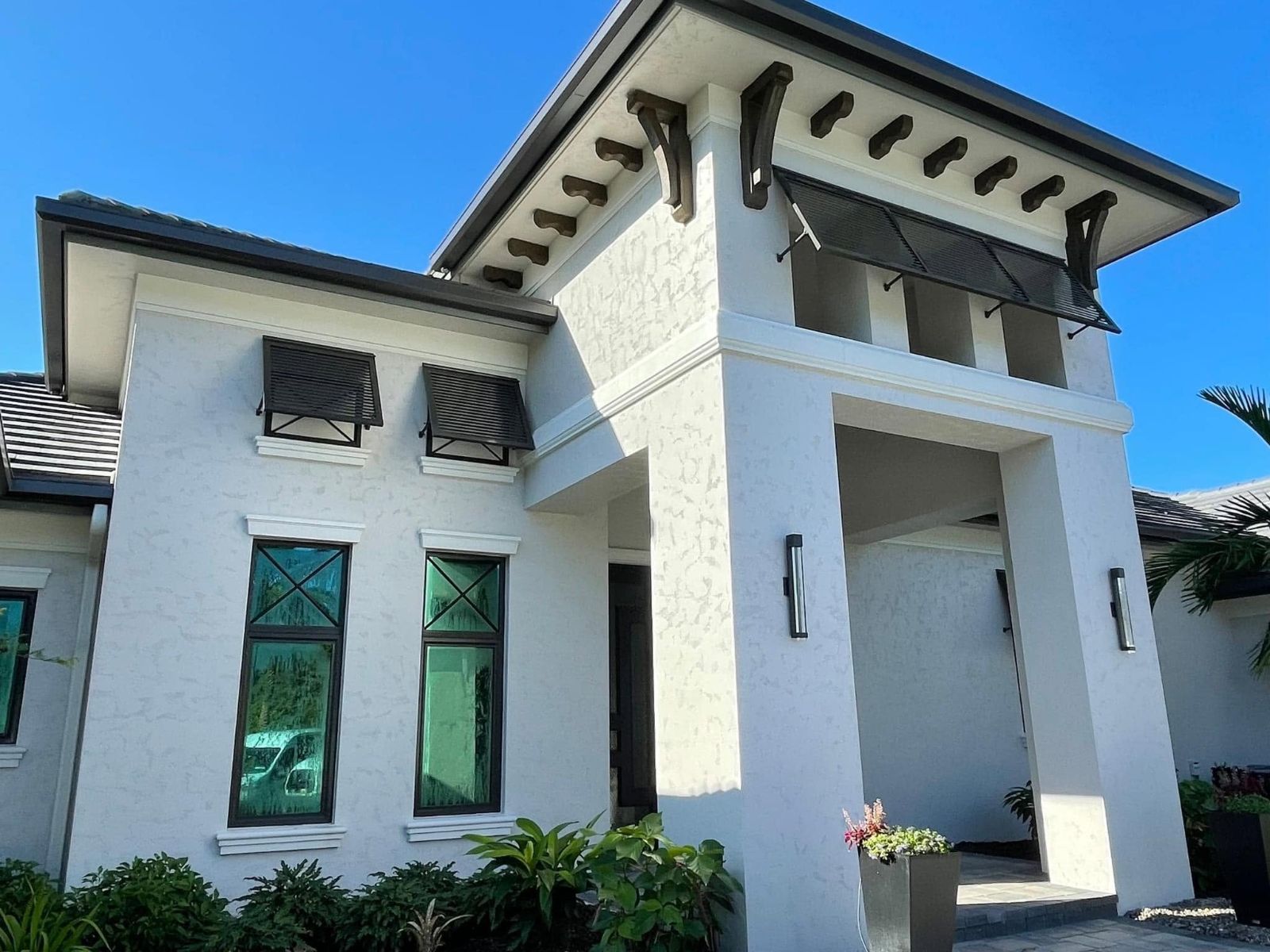White stucco entry with dark bahama shutters
