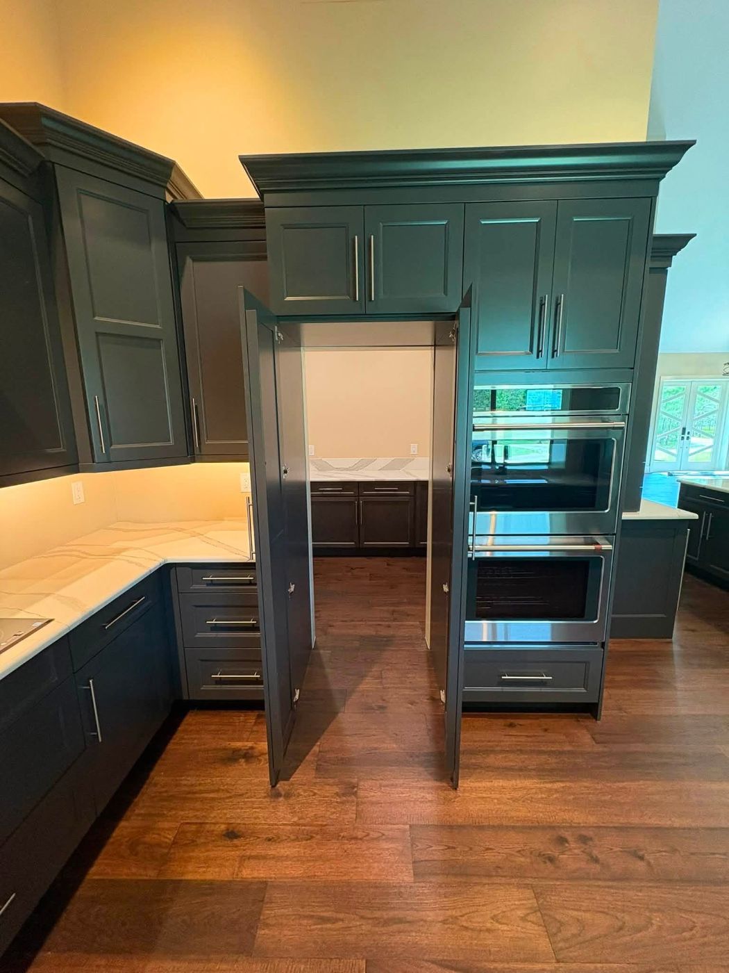 Dark painted kitchen cabinets with hidden pantry doors